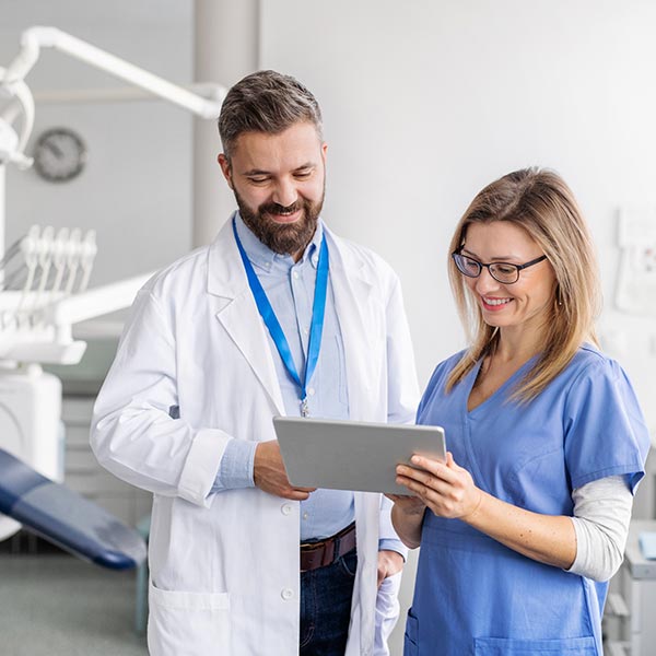 Two Dentalist looking at the tab and smile